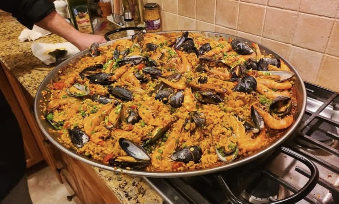 Cast iron paella pan with saffron rice, shrimp, mussels, and lemon